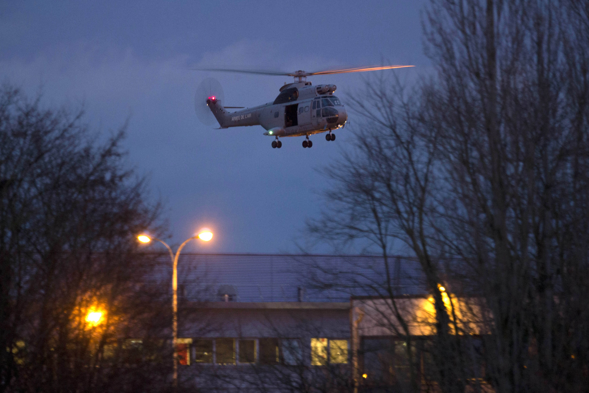 A helicopter flies over a building, where the suspects of a shooting at a Paris newspaper office were holed up, after security forces stormed it in Dammartin-en-Goele, France, Friday Jan. 9, 2015. French police stormed a printing plant north of Paris on Friday, freeing a hostage and killing two brothers linked to al-Qaida who were suspected of slaying 12 people at a Paris newspaper two days ago. (AP Photo/Peter Dejong)