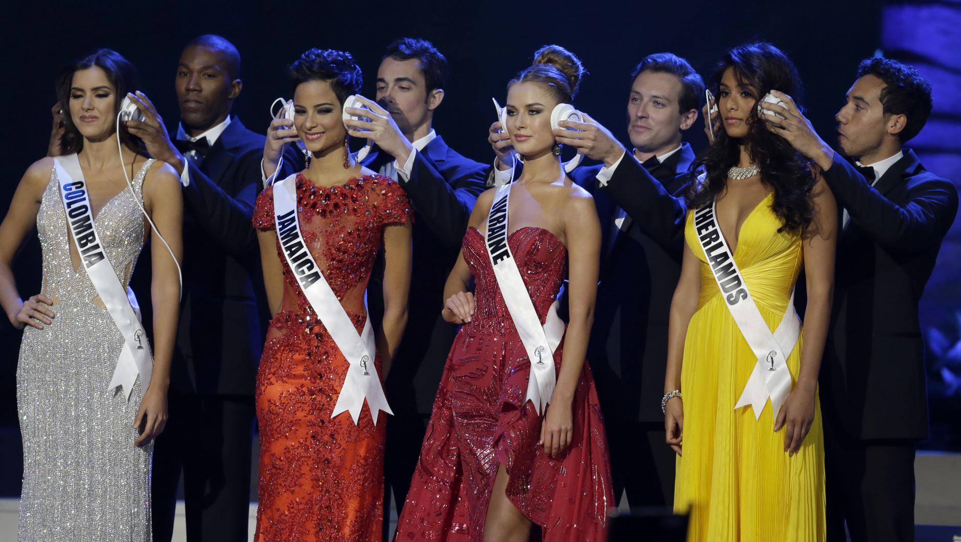 From left, Miss Colombia Paulina Vega, Miss Jamaica  Kaci Fennell, Miss Ukraine Diana Harkusha, and Miss Netherlands Yasmin Verheijen have their ears covered during a question and answer at the Miss Universe pageant in Miami, Sunday, Jan. 25, 2015. (AP Photo/Wilfredo Lee)
