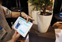 Jerome Bouvard demonstrates the Parrot Pot at CES Unveiled, a media preview event for CES International, Sunday, Jan. 4, 2015, in Las Vegas. The pot is linked to mobile devices and will automatically water your plant. (AP Photo/John Locher)