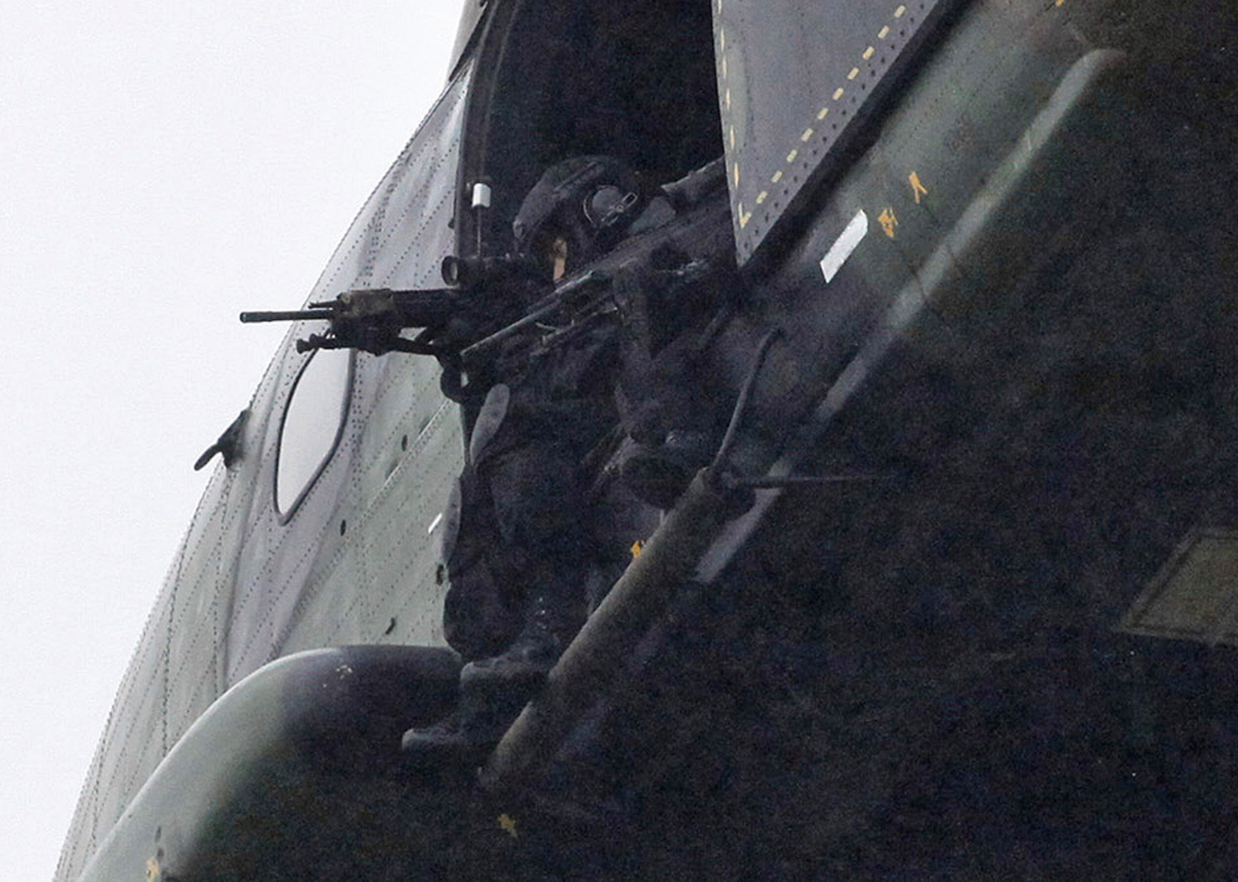 Armed security forces fly overhead in a military helicopter  in Dammartin-en-Goele, northeast of Paris, Friday Jan. 9, 2015.   French security forces swarmed this small industrial town northeast of Paris Friday in an operation to capture a pair of heavily armed suspects in the deadly storming of a satirical newspaper. (AP Photo/Thibault Camus)