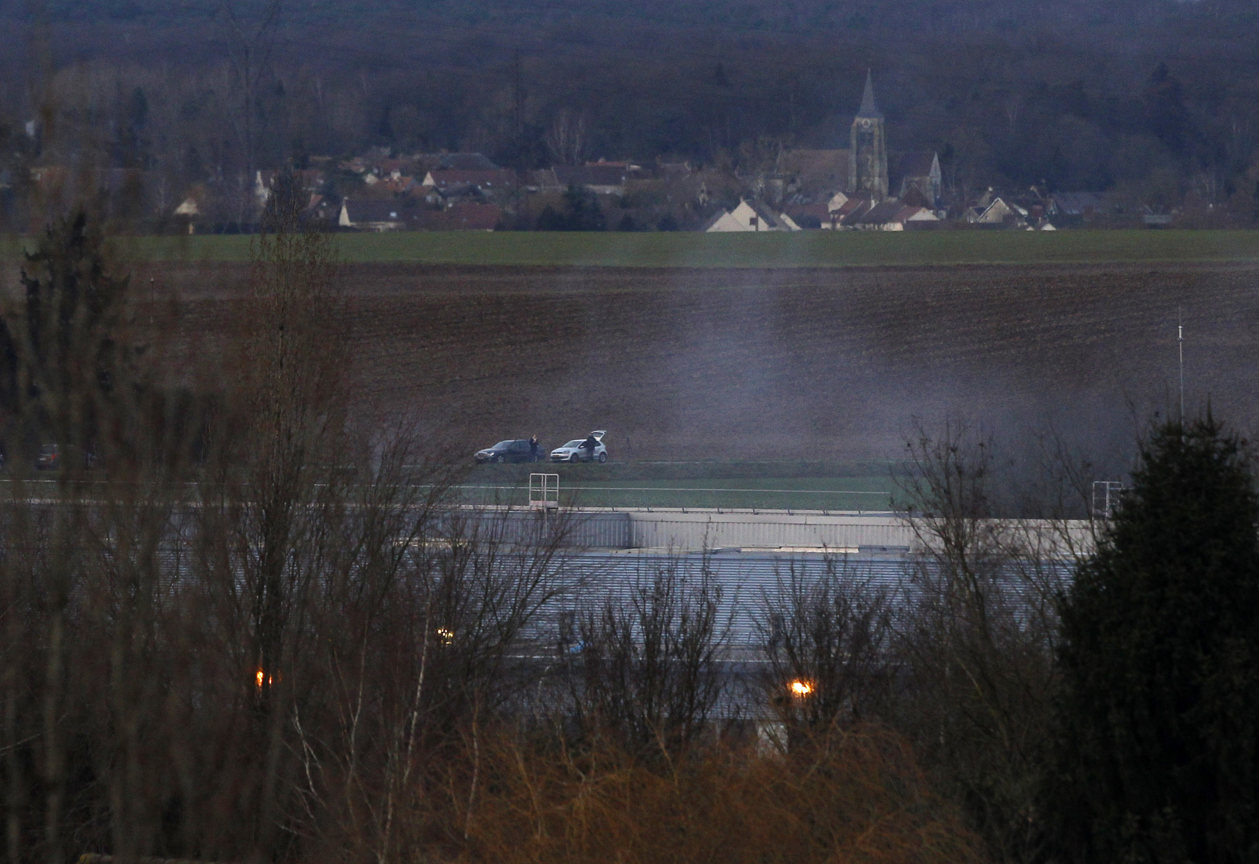Smoke rises from a building in Dammartin-en-Goele, northeast of Paris, where the two brothers suspected in a deadly terror attack were cornered, Friday, Jan. 9, 2015. Explosions and gunshots rang out and smoke rose outside a building where two brothers suspected in a newspaper massacre are holed up with a hostage. (AP Photo/Michel Spingler)