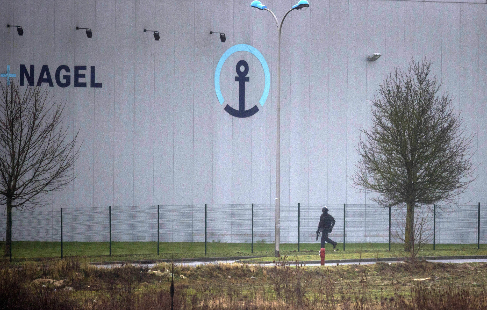 An armed member of the security forces walks inside Dammartin-en-Goele, northeast of Paris, Friday Jan.9, 2015.   French security forces swarmed the small industrial town northeast of Paris Friday in an operation to capture a pair of heavily armed suspects in the deadly storming of a satirical newspaper. (AP Photo/Peter Dejong)