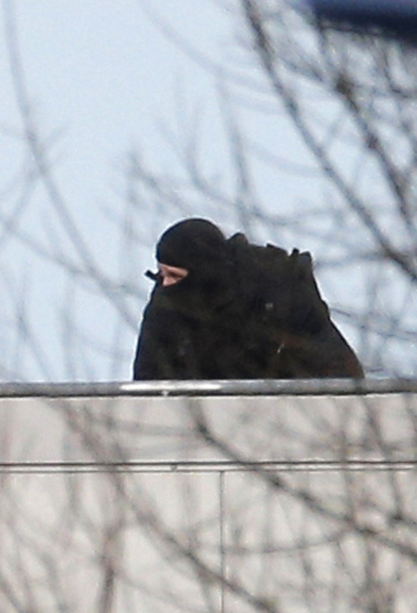 A hooded police officer stands on a roof in Dammartin-en-Goele, northeast of Paris, where the two brothers suspected in a deadly terror attack were cornered, Friday, Jan.9, 2015. Two sets of attackers seized hostages and locked down hundreds of French security forces around the capital on Friday, sending the city into fear and turmoil for a third day in a series of linked attacks that began with the deadly newspaper terror attack that left 12 people dead. (AP Photo/Christophe Ena)