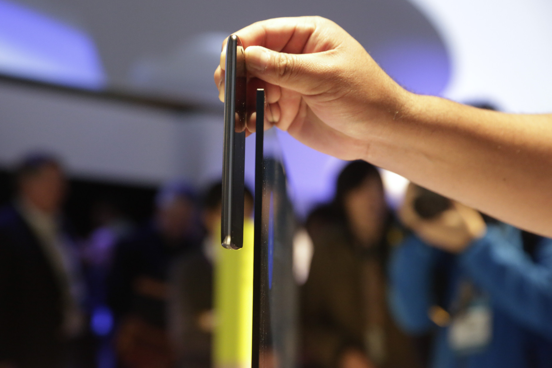 An attendee places his smartphone next to Sony's 65-inch X900 C series 4K Ultra HD TV to compare the thickness at the Sony booth at the International CES Monday, Jan. 5, 2015, in Las Vegas. The display is less than 0.2 inches thick at its slimmest point. (AP Photo/Jae C. Hong)