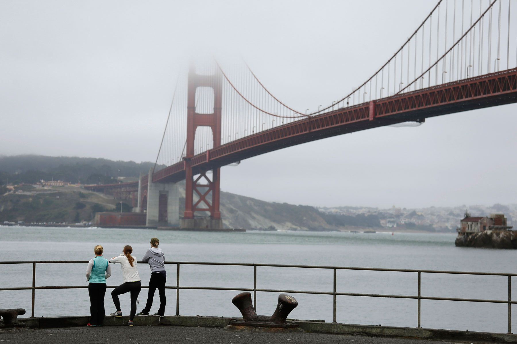 Three women stand at the end of a fishing pier at Fort Baker and look out at the Golden Gate Bridge Monday, Aug. 18, 2014, near Sausalito, Calif. (AP Photo/Eric Risberg)