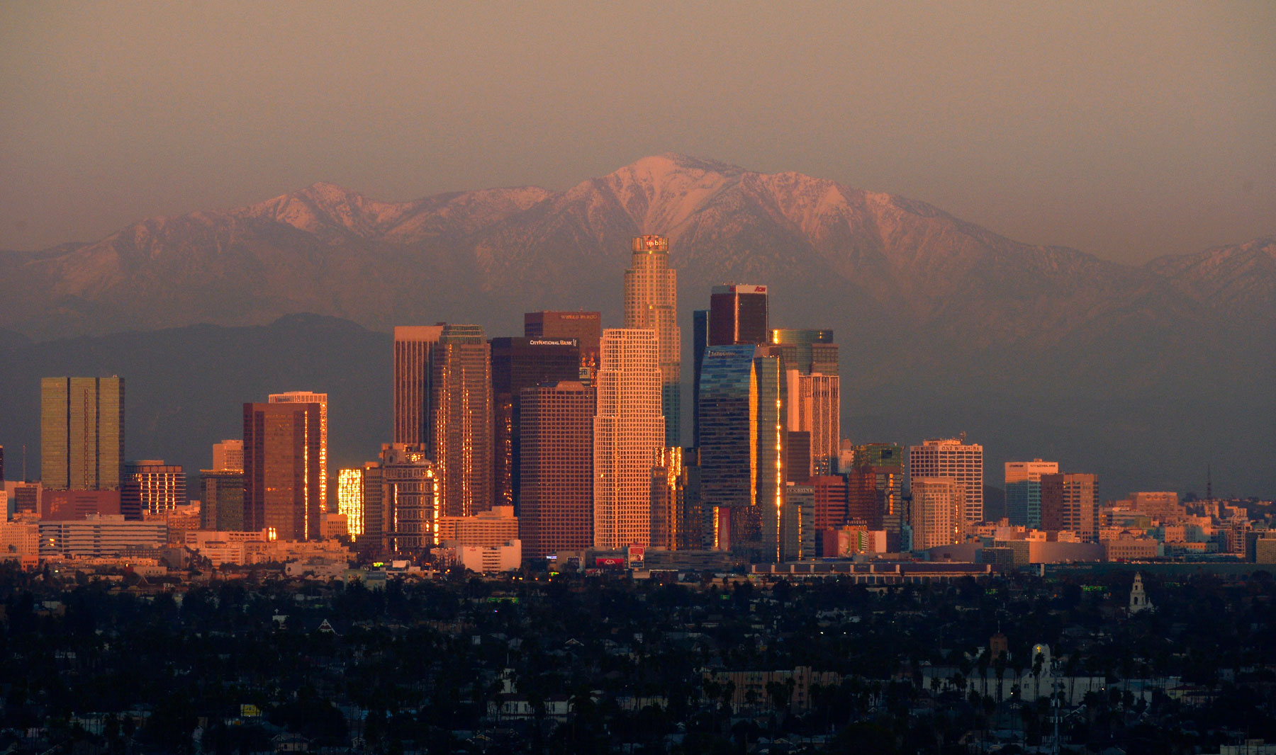 The sun sets over downtown Los Angeles skyline with the snow covered mountains behind it, Thursday, Jan. 3, 2013, in Los Angeles. (AP Photo/Mark J. Terrill)