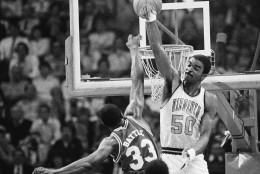 Virginia's Ralph Sampson swats and misses the basketball Sunday, March 14, 1983 as N.C. State's Alvin Battle drives past him to score at Atlanta Omni. North Carolina State won the championship of the Atlantic Coast Conference tournament, 81-78. (AP Photo/Bob Jordan)