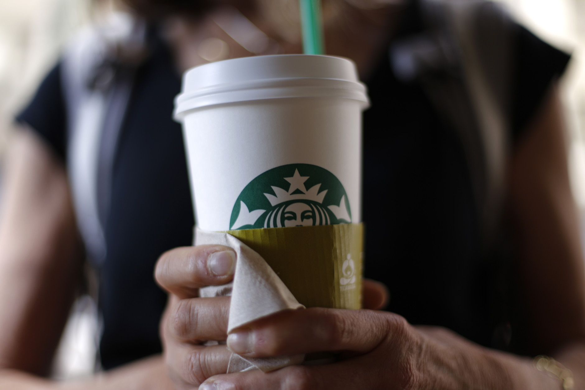 In this May 31, 2014 photo, a woman holds a coffee drink outside a Starbucks in downtown Chicago. Starbucks is raising prices on some of its drinks by 5 cents to 20 cents starting next week, and customers can also soon expect to pay $1 more for the packaged coffee it sells in supermarkets. Prices for medium and large brewed coffees, which are known as Grande and Venti, respectively, will go up between 10 cents and 15 cents in most U.S. markets, the company said.  (AP Photo/Gene J. Puskar)