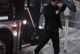 man gets off bus in rain