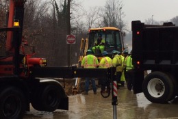 Men work to repair a water main break that occurred early Monday in Arlington on U.S. 29 at the bottom of the ramp from eastbound I-66 eastbound to Spout Run.  (WTOP/Rob Stallworth)