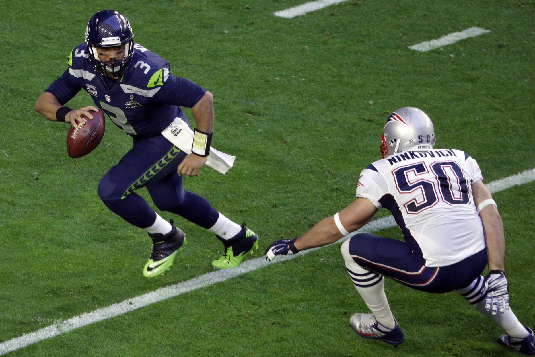 Seattle Seahawks quarterback Russell Wilson (3) scrambles away from New England Patriots defensive end Rob Ninkovich (50) during the first half of NFL Super Bowl XLIX football game Sunday, Feb. 1, 2015, in Glendale, Ariz. (AP Photo/Charlie Riedel)