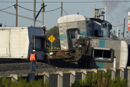 A worker walks along the tracks near the wreck of a Metrolink passenger train that derailed, Tuesday, Feb. 24, 2015, in Oxnard, Calif. Three cars of the Metrolink train tumbled onto their sides, injuring dozens of people in agricultural country 65 miles northwest of Los Angeles. Metrolink spokesman Scott Johnson told the Los Angeles Times that at least 30 people were injured. (AP Photo/Mark J. Terrill)