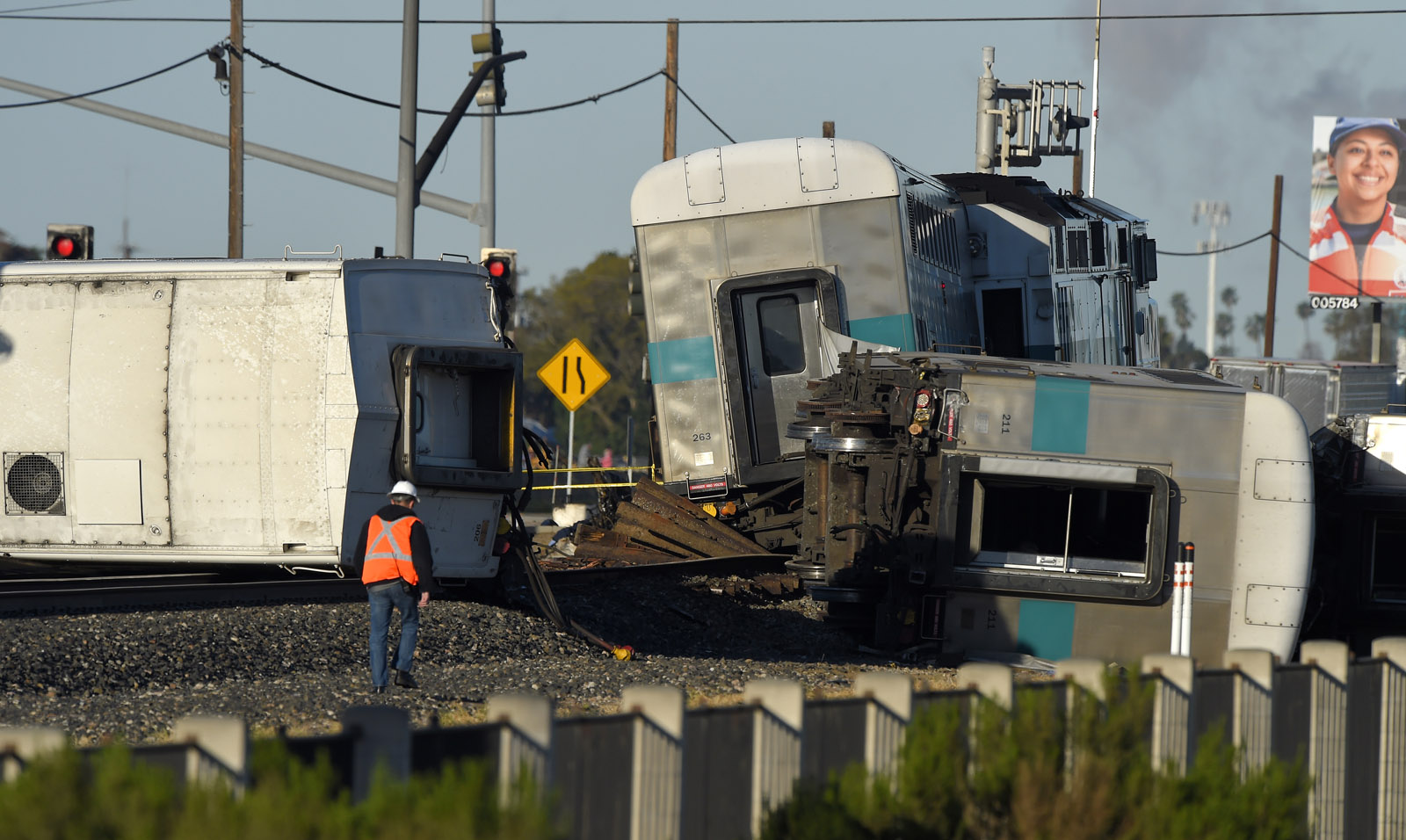A worker walks along the tracks near the wreck of a Metrolink passenger train that derailed, Tuesday, Feb. 24, 2015, in Oxnard, Calif. Three cars of the Metrolink train tumbled onto their sides, injuring dozens of people in agricultural country 65 miles northwest of Los Angeles. Metrolink spokesman Scott Johnson told the Los Angeles Times that at least 30 people were injured. (AP Photo/Mark J. Terrill)