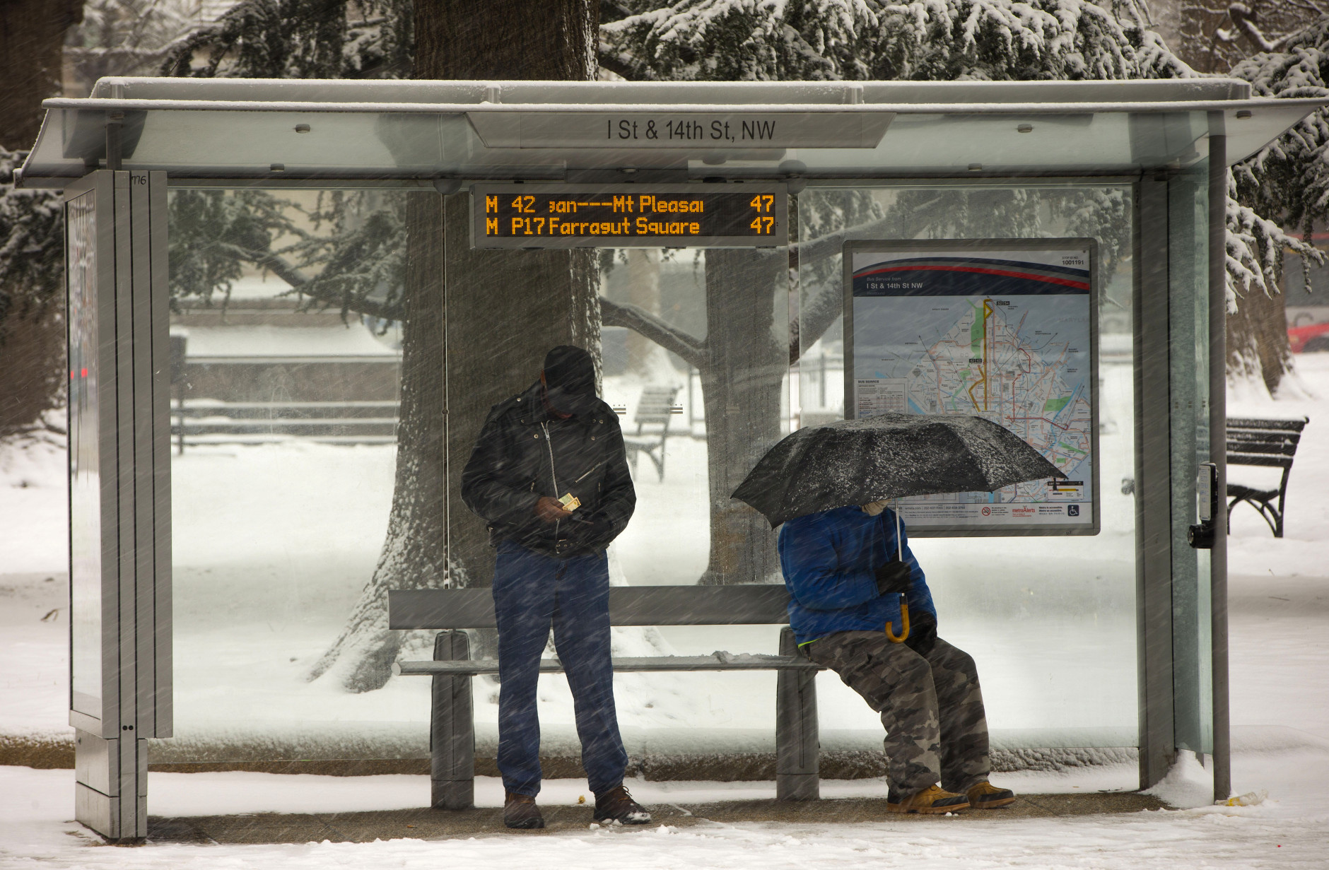 People wait in the falling snow at the bus stop in downtown Washington, Thursday, Feb. 26, 2015. (AP Photo/Pablo Martinez Monsivais)