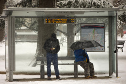 People wait in the falling snow at the bus stop in downtown Washington, Thursday, Feb. 26, 2015. (AP Photo/Pablo Martinez Monsivais)