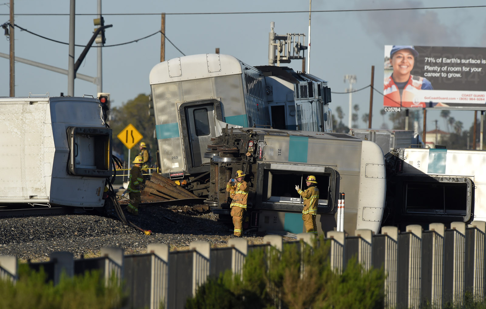 Firefighter stand in front of the wreck of a Metrolink passenger train that derailed, Tuesday, Feb. 24, 2015, in Oxnard, Calif. Three cars of the Metrolink train tumbled onto their sides, injuring dozens of people in agricultural country 65 miles northwest of Los Angeles. Metrolink spokesman Scott Johnson told the Los Angeles Times that at least 30 people were injured. (AP Photo/Mark J. Terrill)