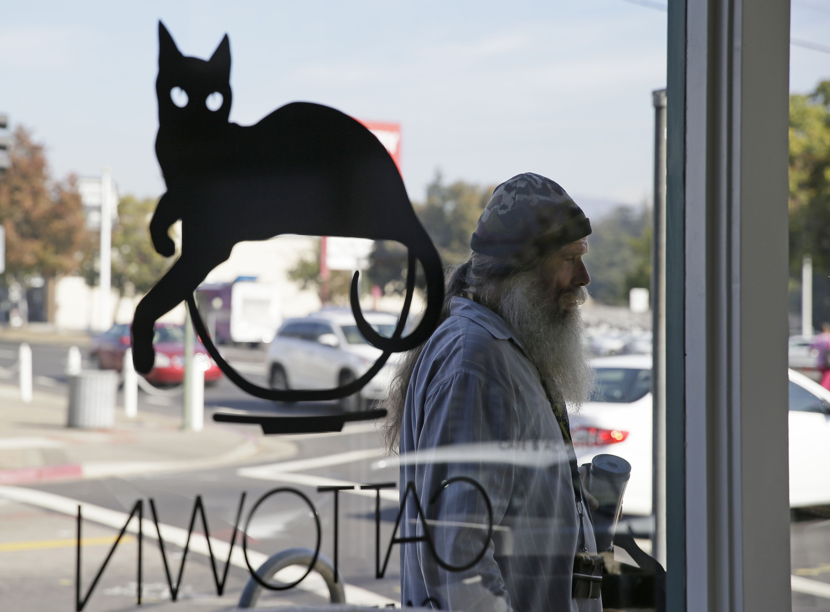 In this photo taken Thursday, Nov. 6, 2014, a man passes by and looks in the windows of people playing with cats at the Cat Town Cafe in Oakland, Calif. Following similar cafe concepts in Asia &amp; Europe, the cafe has become America's first permanent feline-friendly coffee shop. Cafe customers pay to pet cute kitties while sipping on tea or expresso drinks. It allows customers, who may not be able to have cats in their own homes, to enjoy the benefits of furry friends for short times without the responsibility. The animals come from a partnership with a local animal shelter and are also available for adoption. Similar cafes are planned to open soon in Seattle, Portland, San Diego and Denver. (AP Photo/Eric Risberg)