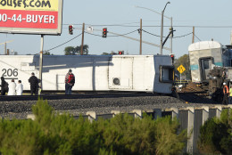 Passengers stand near the wreck of a Metrolink passenger train that derailed, Tuesday, Feb. 24, 2015, in Oxnard, Calif. Three cars of the Metrolink train tumbled onto their sides, injuring dozens of people in agricultural country 65 miles northwest of Los Angeles. Metrolink spokesman Scott Johnson told the Los Angeles Times that at least 30 people were injured. (AP Photo/Mark J. Terrill)