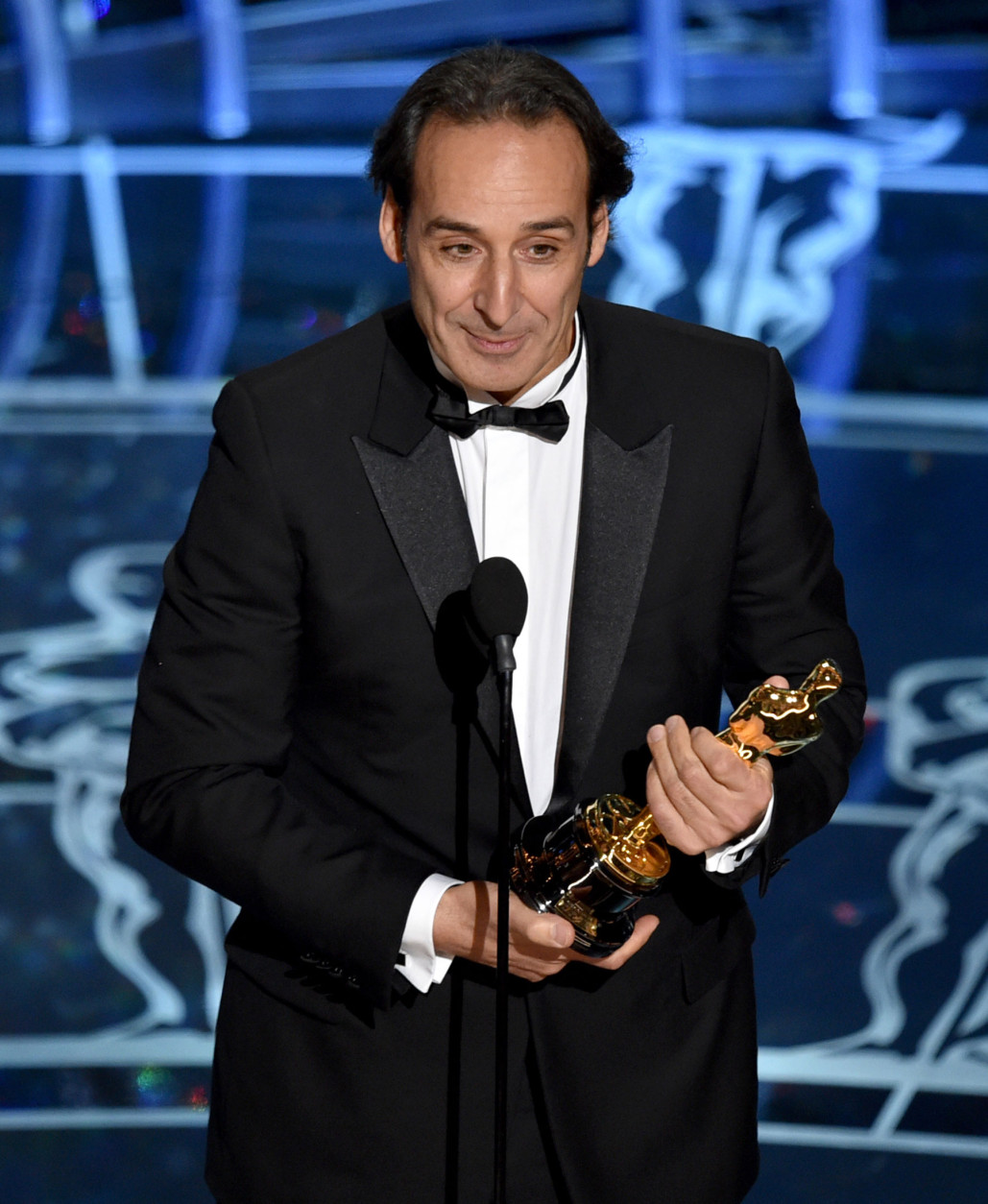 Alexandre Desplat accepts the award for original score in a feature film for “The Grand Budapest Hotel” at the Oscars on Sunday, Feb. 22, 2015, at the Dolby Theatre in Los Angeles. (Photo by John Shearer/Invision/AP)