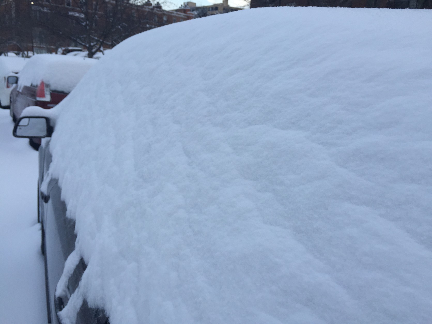 Cars are covered in a thick layer of snow in Northwest D.C. Tuesday morning. (WTOP/Neal Augenstein)