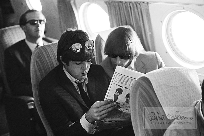 Paul McCartney and Ringo Starr are wonderfully unaware in this candid photograph of them reading a magazine on a plane, en route to their show at Cow Palace outside of San Francisco, California, on August 30, 1965. Also on the plane from Hollywood with the Beatles was Joan Baez, who visited them backstage in San Francisco. In the weeks before, the Beatles had played 16 shows in nine cities to more than 300,000 screaming teenage fans. The San Francisco shows would be their last before a much-needed six-week break before getting back in the studio to record Rubber Soul. Their double-header at Cow Palace drew 11,700 fans in the afternoon and 17,000 more that night—and even had to be stopped for ten minutes after fans pushed through the barricades and rushed the stage. With the Cow Palace show the band had really come full circle, as they were closing out their second US tour exactly where they had opened their first in August 1964. 