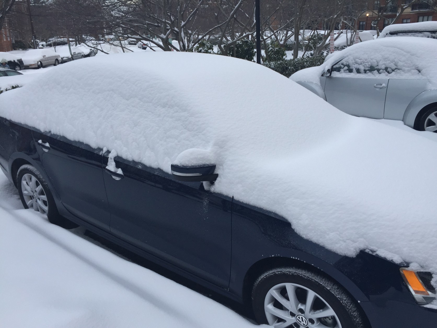 Snowy cars are parked in a D.C. parking lot Tuesday morning. (WTOP/Neal Augenstein)