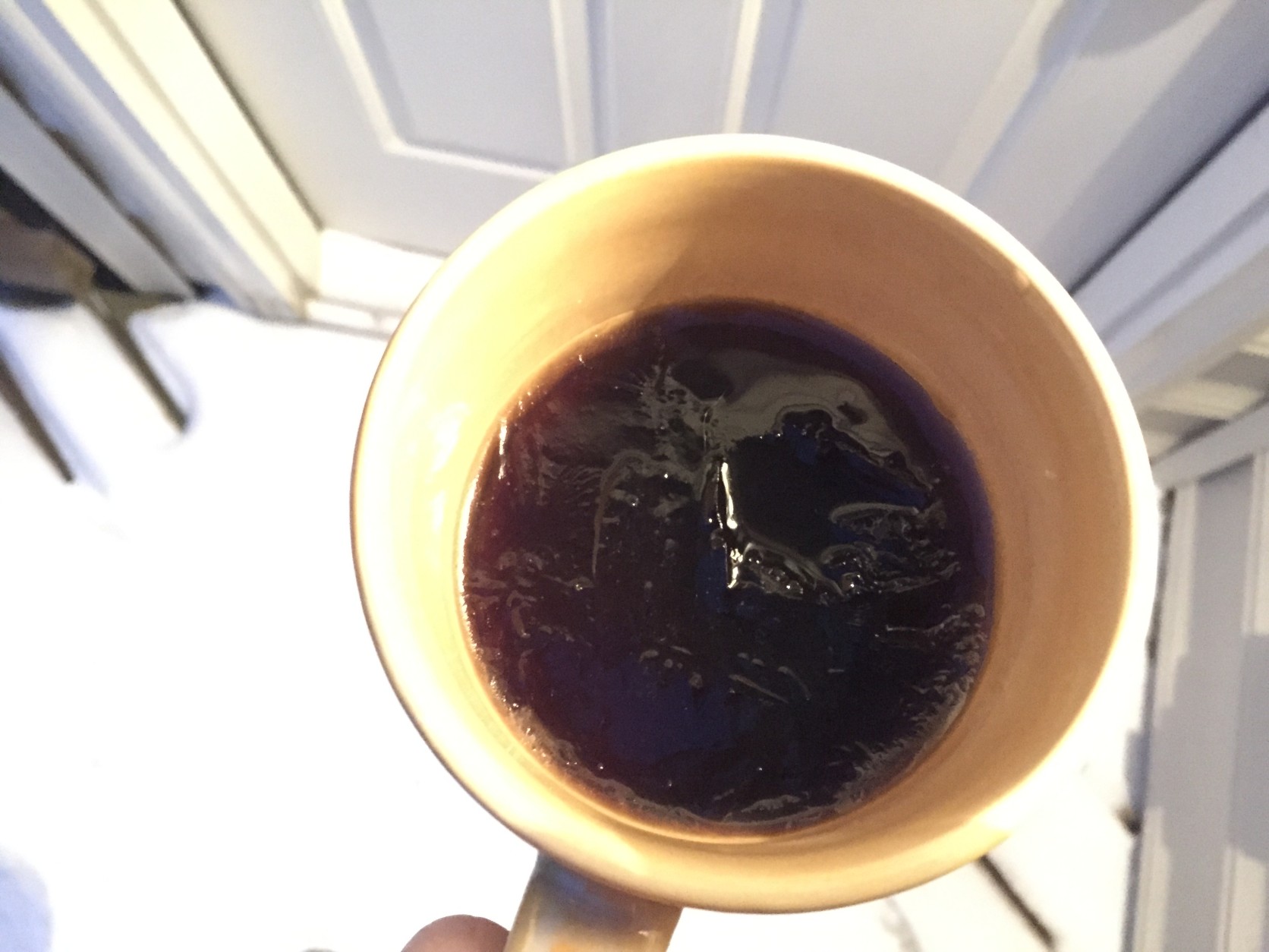 The once-steaming cup of hot black coffee has thin layer of ice, 90 minutes after being left in 10 degree weather. (WTOP/Neal Augenstein)