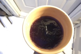 The once-steaming cup of hot black coffee has thin layer of ice, 90 minutes after being left in 10 degree weather. (WTOP/Neal Augenstein)