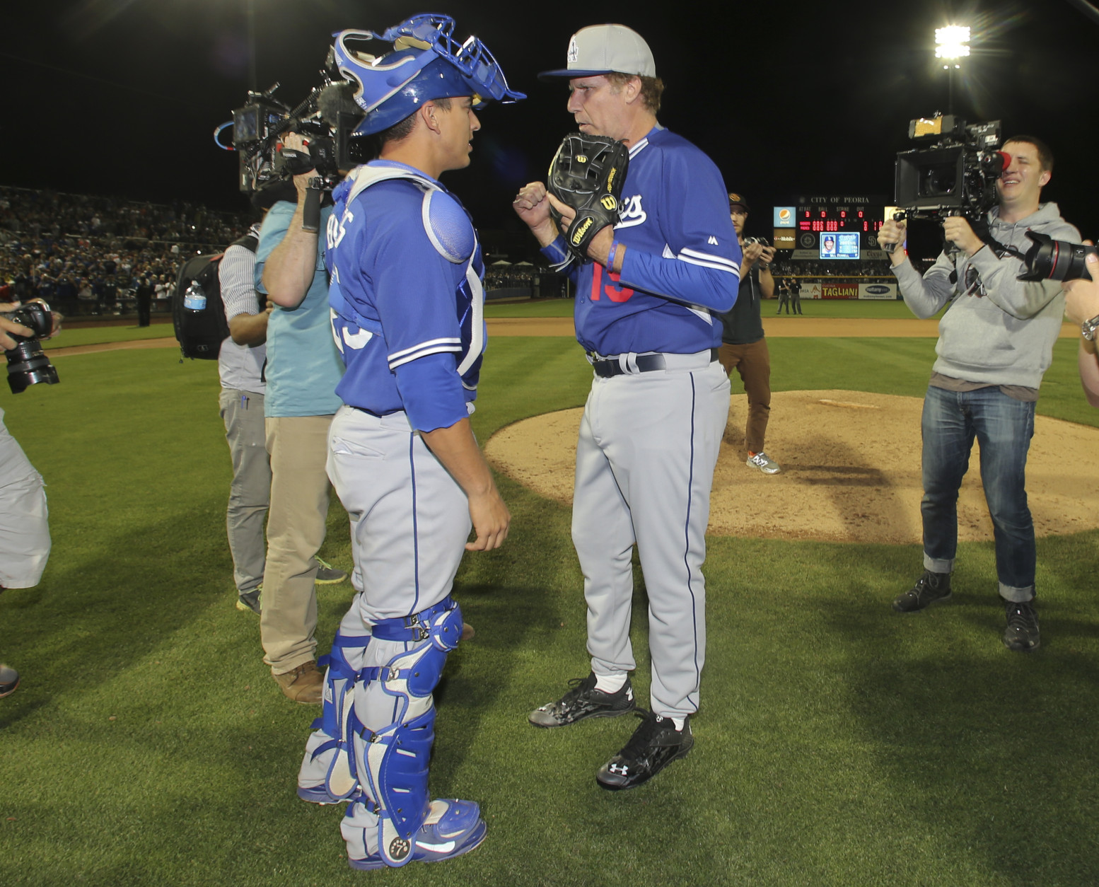 Actor Will Ferrell has a meeting with Los Angeles Dodgers catcher A.J. Ellis before he warms up to pitch against the San Diego Padres in a spring training baseball game Thursday, March 12, 2015, in Peoria, Ariz.  (AP Photo/Lenny Ignelzi)