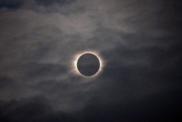 A total solar eclipse is visible through the clouds as seen from Vagar on the Faeroe Islands, Friday, March 20, 2015.  Apart from a few small breaks, a blanket of clouds in the Faeroe Islands blocked thousands of people there from experiencing the full effect of the total eclipse.  (AP Photo/Eric Adams)