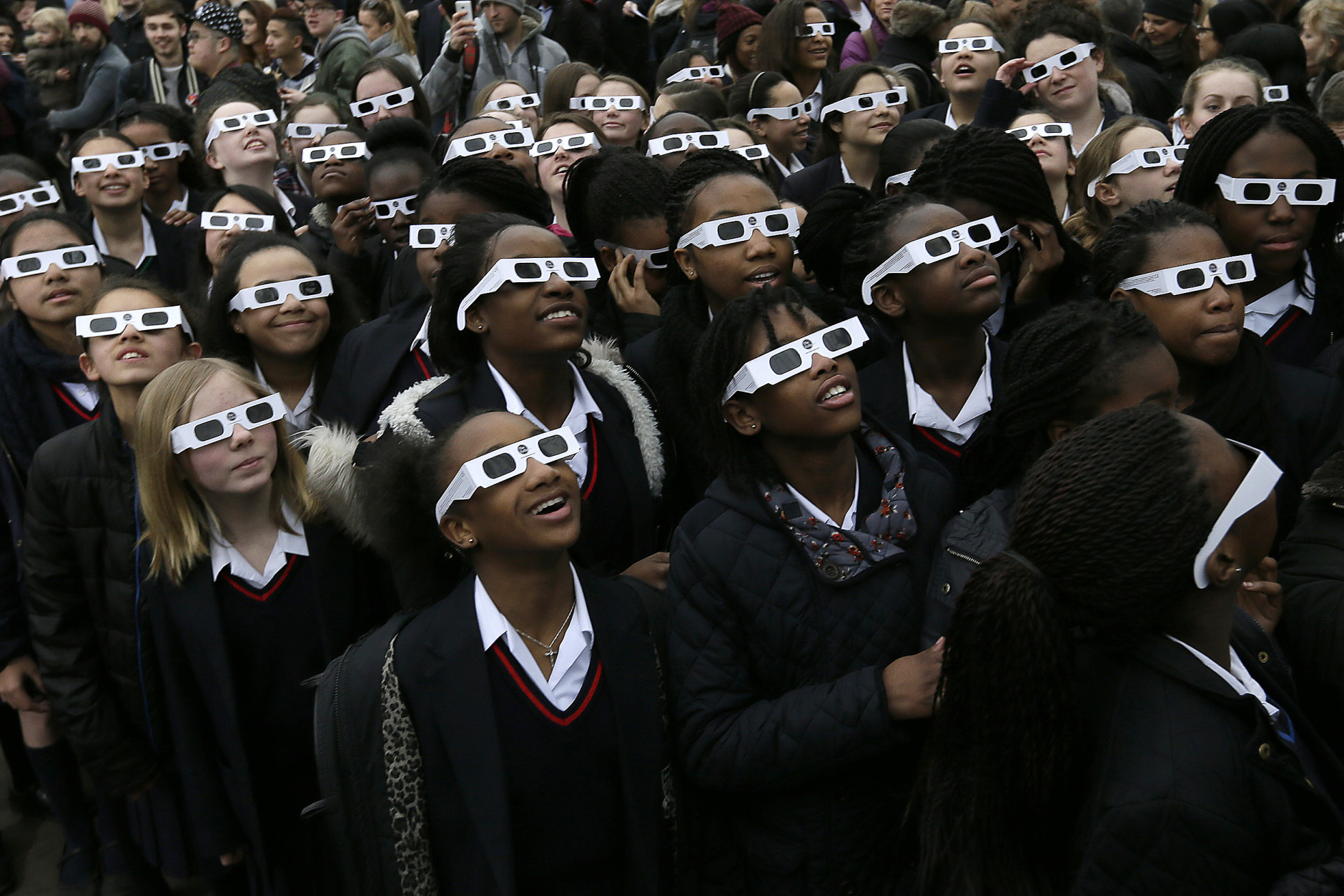 Schoolchildren pose for photographers at the Royal Observatory in Greenwich Park, as people gather to try to see the solar eclipse in London, Friday, March 20, 2015. In the capital, thick cloud cover obscured a view of the sun. (AP Photo/Tim Ireland)
