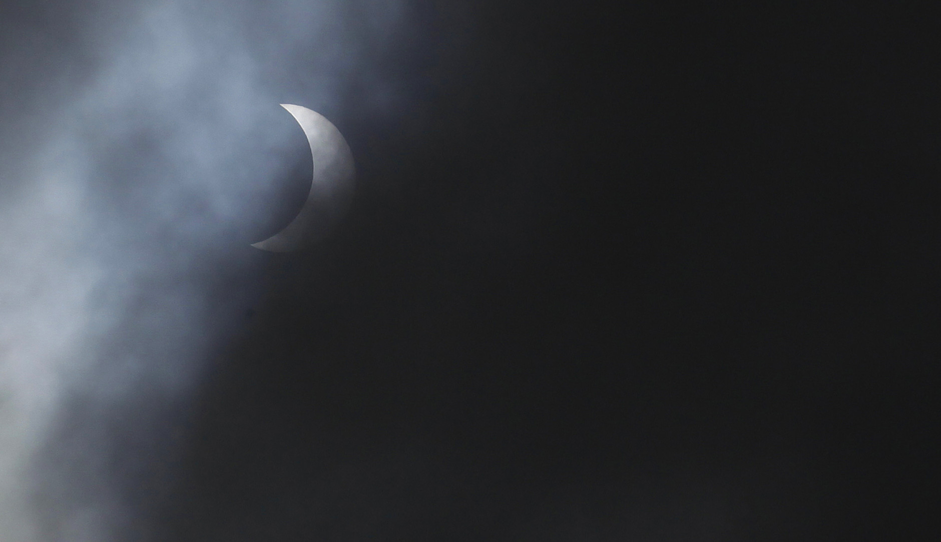 The solar eclipse is seen through the clouds at Queens University, Belfast, Northern Ireland, Friday, March 20, 2015.  People across Northern Ireland were treated to a rare glimpse of an almost total solar eclipse early Friday.   (AP Photo/Peter Morrison)