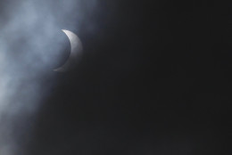 The solar eclipse is seen through the clouds at Queens University, Belfast, Northern Ireland, Friday, March 20, 2015.  People across Northern Ireland were treated to a rare glimpse of an almost total solar eclipse early Friday.   (AP Photo/Peter Morrison)