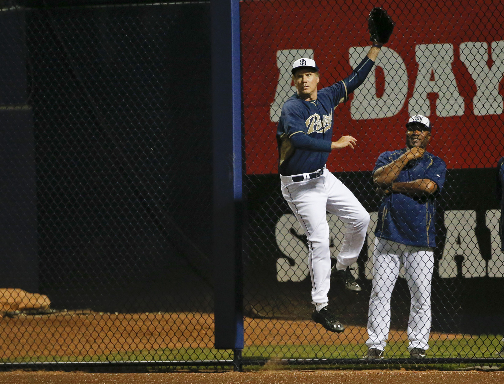 Actor Will Ferrell, playing right field for the San Diego Padres in a spring training baseball game, leaps at the right field fence long ax a home run by Los Angeles Dodgers' Joc Pederson cleared the fence by a wide margin Thursday, March 12, 2015, in Peoria, Ariz. (AP Photo/Lenny Ignelzi)