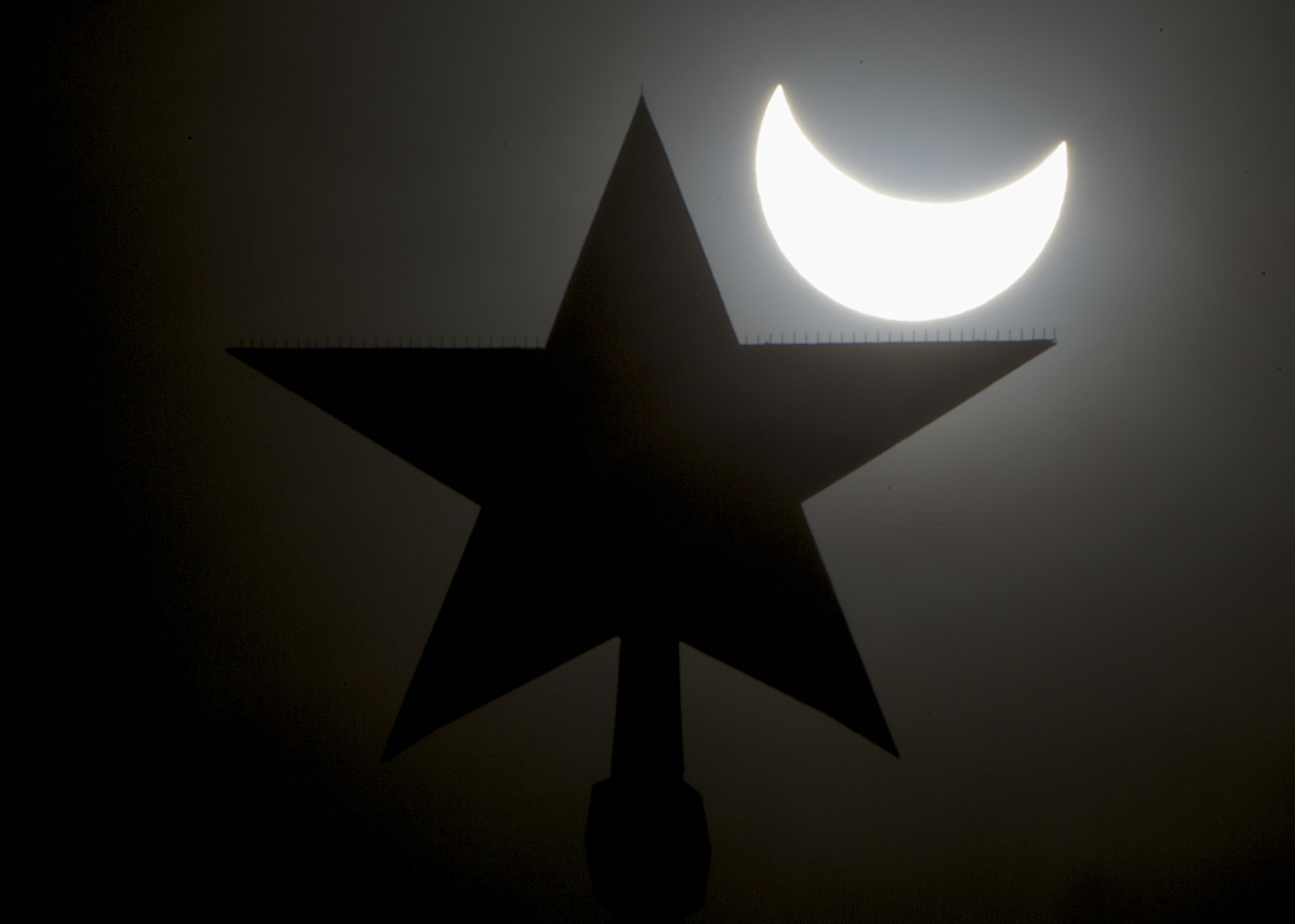 The moon blocks part of the sun during a solar eclipse as seen over Moscow Kremlin's Troitskaya (Trinity) tower, in Russia, on Friday, March 20, 2015. (AP Photo/Pavel Golovkin)