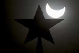 The moon blocks part of the sun during a solar eclipse as seen over Moscow Kremlin's Troitskaya (Trinity) tower, in Russia, on Friday, March 20, 2015. (AP Photo/Pavel Golovkin)