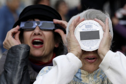 People look at a solar eclipse in the sky of Nice, southeastern France, Friday, March 20, 2015. An eclipse is darkening parts of Europe on Friday in a rare solar event that won't be repeated for more than a decade. (AP Photo/Lionel Cironneau)