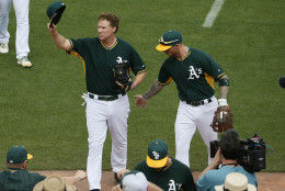 Actor Will Ferrell, left, tips his cap after playing shortstop for the Oakland Athletics during the first inning of a spring training baseball game against the Seattle Mariners, Thursday, March 12, 2015, in Mesa, Ariz. The comedian plans to play every position while making appearances at five Arizona spring training games on Thursday. (AP Photo/Matt York)