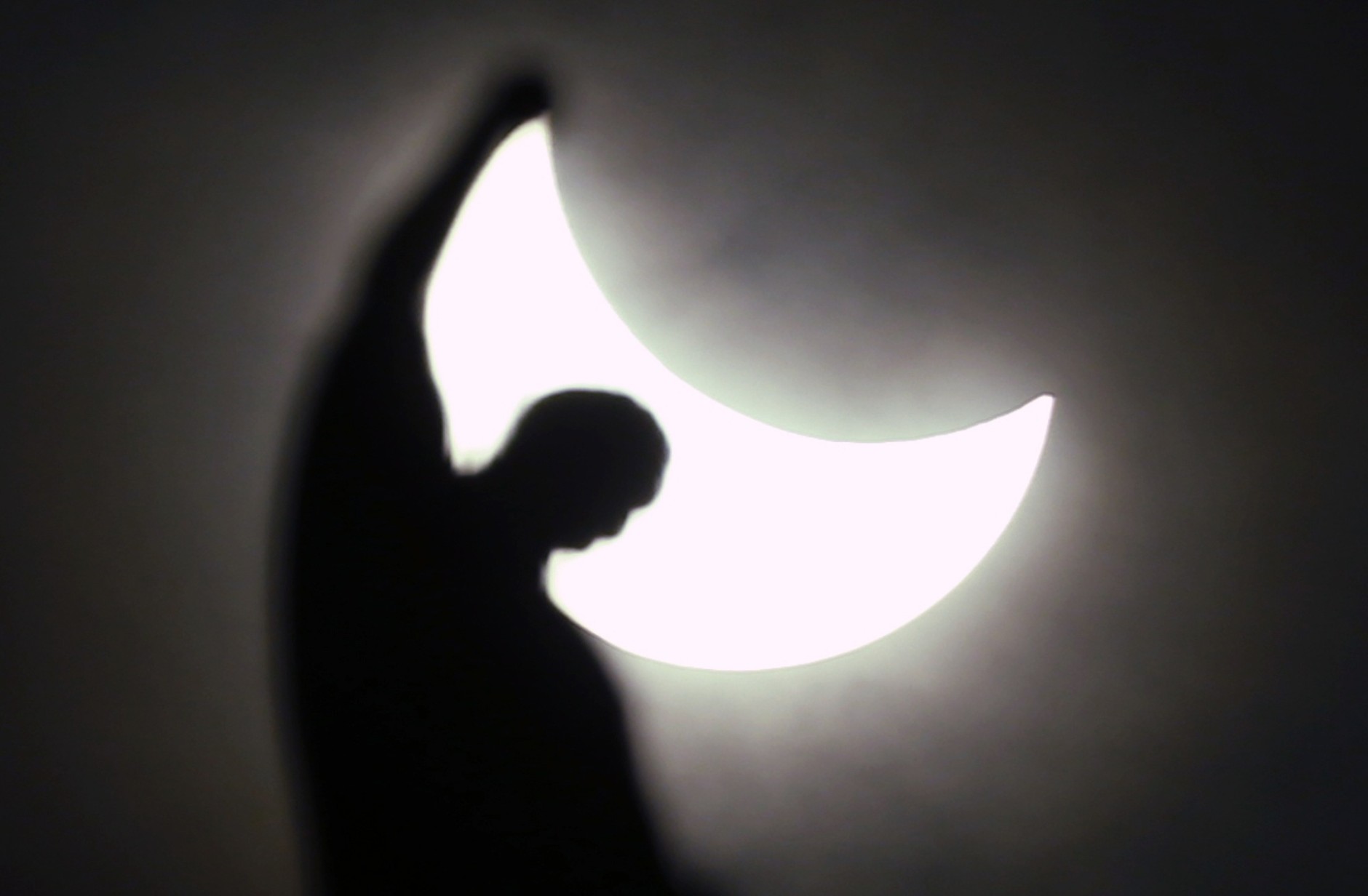 The moon starts to block the sun during a solar eclipse over a statue of the Duomo gothic cathedral in Milan, Italy, Friday, March 20, 2015. An eclipse is darkening parts of Europe on Friday in a rare solar event that won't be repeated for more than a decade. (AP Photo/Luca Bruno)