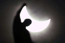 The moon starts to block the sun during a solar eclipse over a statue of the Duomo gothic cathedral in Milan, Italy, Friday, March 20, 2015. An eclipse is darkening parts of Europe on Friday in a rare solar event that won't be repeated for more than a decade. (AP Photo/Luca Bruno)