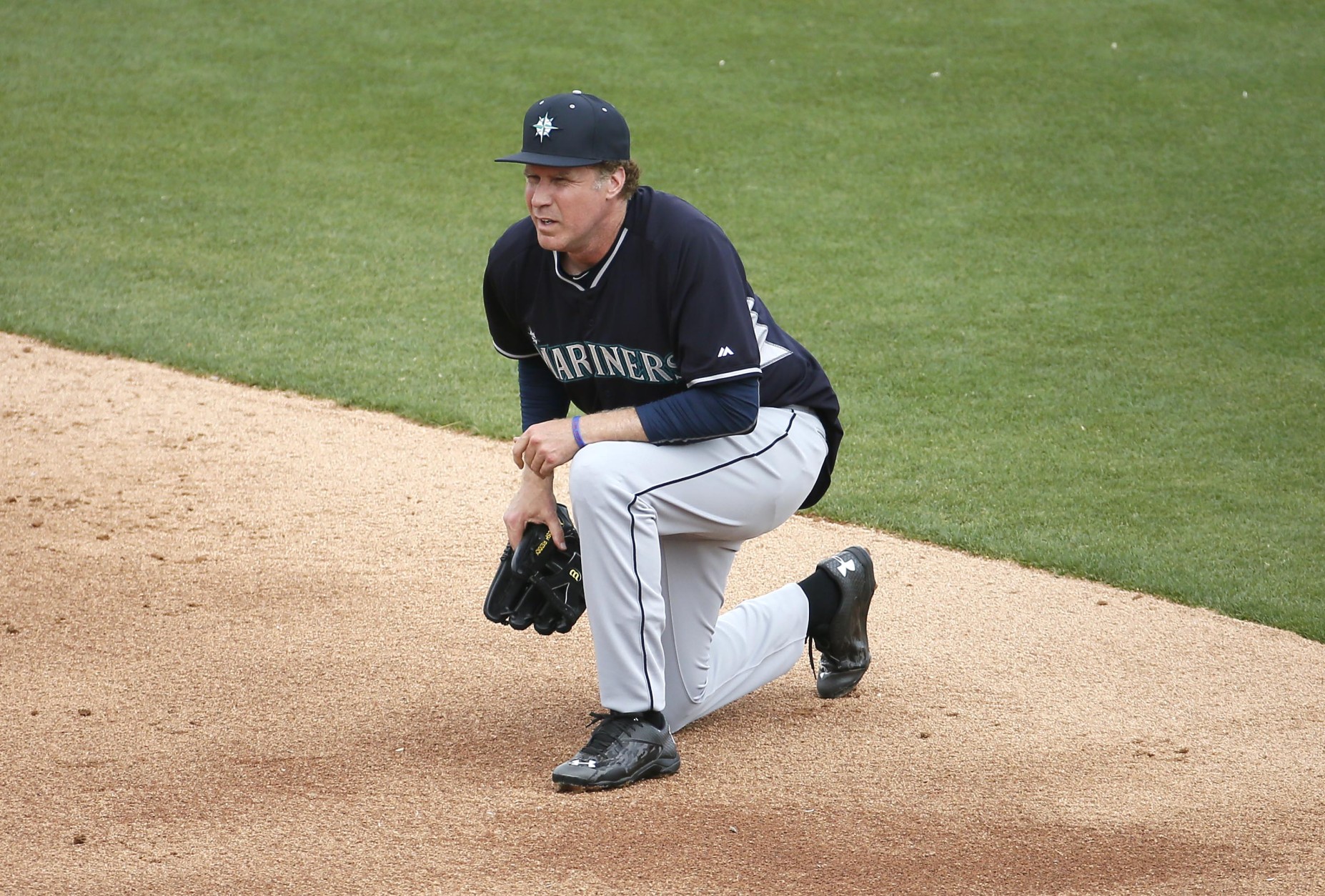 Actor Will Ferrell takes a knee while playing second base for the Seattle Mariners during the second inning of a spring training baseball game against the Oakland A's, Thursday, March 12, 2015, in Mesa, Ariz. Ferrell is filming a new special from Funny Or Die, in partnership with Major League Baseball, to air exclusively on HBO later this year. (AP Photo/Matt York)