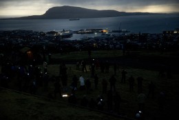 People watch in darkness during the totality of a solar eclipse on as seen from a hill beside a hotel on the edge of the city overlooking Torshavn, the capital city of the Faeroe Islands, Friday, March 20, 2015. For months, even years, accommodation on the remote Faeroe Islands has been booked out by fans who don't want to miss an almost three-minute-long astronomical sensation. Now they just have to hope the clouds will blow away so they can fully experience Friday's brief total solar eclipse.  (AP Photo/Matt Dunham)