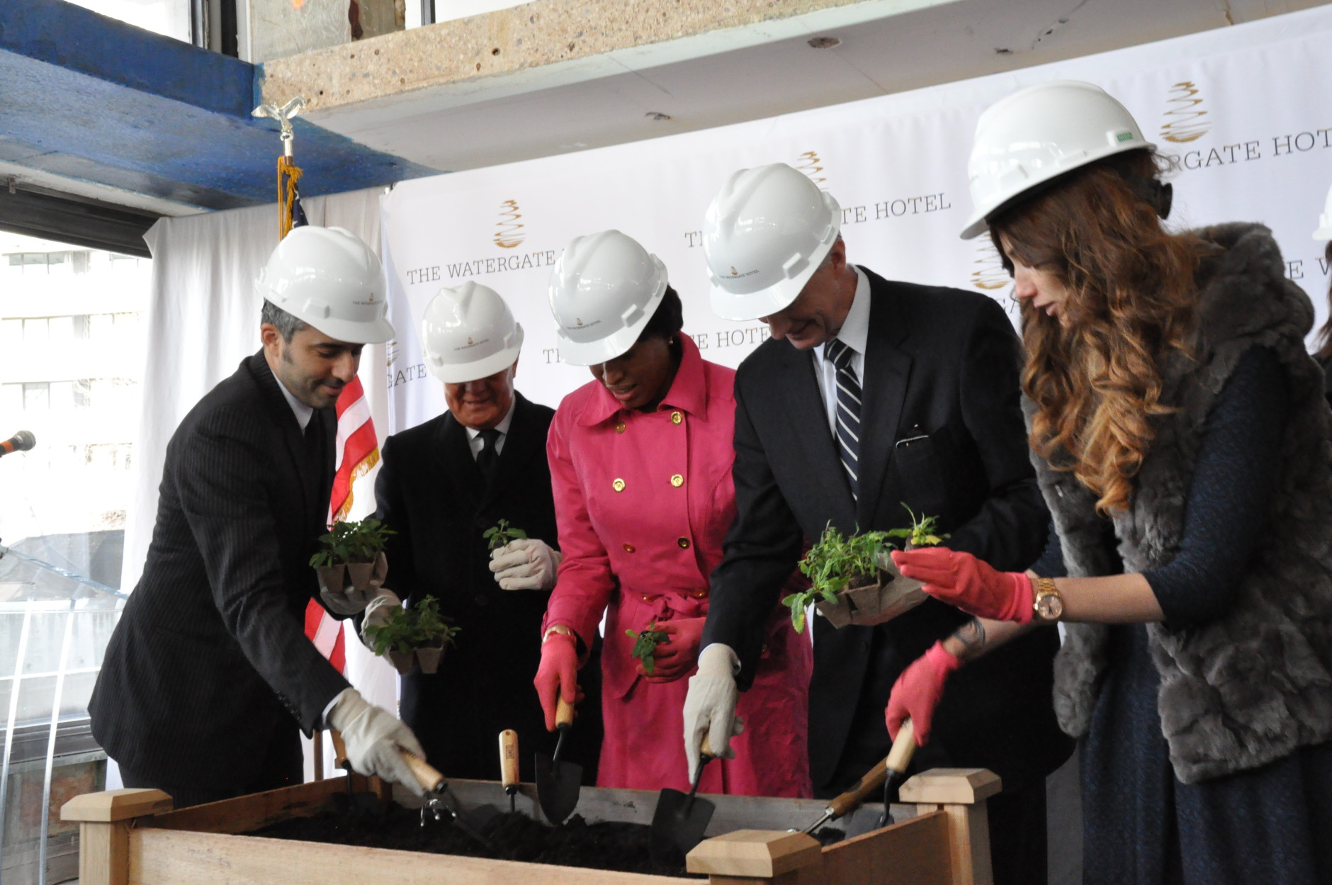 At the hotel's topping off event on Thursday, owner/developer Jacques Cohen, Managing Director Johnny So, D.C. Mayor Muriel Bowser, D.C. Councilmember Jack Evans and owner/developer Rakel Cohen plant seeds that will be used for the hotel's landscaping. (WTOP/Rachel Nania) 