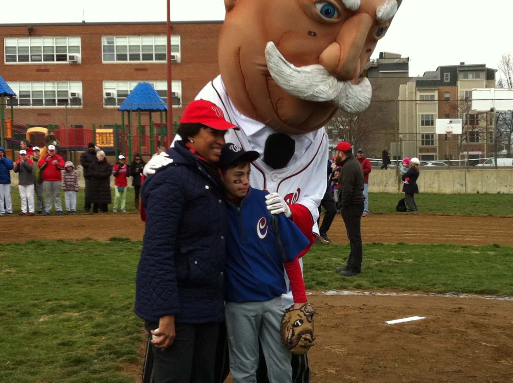 Muriel Bowser poses with a Little League baseball member and “Big Chief Taft” after the first pitch.