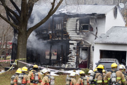 Montgomery County, Md., firefighters stand outside a house where a small private jet crashed in Gaithersburg, Md., Monday, Dec. 8, 2014. A woman and her two young sons inside the home and three people on the aircraft were killed, authorities said. (AP Photo/Jose Luis Magana)