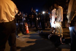 BALTIMORE, MD - APRIL 28:  A protestor lies in front of a police barricade blocking the exit of a vehicle the night after citywide riots over the death of Freddie Gray on April 28, 2015 in Baltimore, Maryland. Freddie Gray, 25, was arrested for possessing a switch blade knife April 12 outside the Gilmor Houses housing project on Baltimore's west side. According to his attorney, Gray died a week later in the hospital from a severe spinal cord injury he received while in police custody. (Photo by Mark Makela/Getty Images)