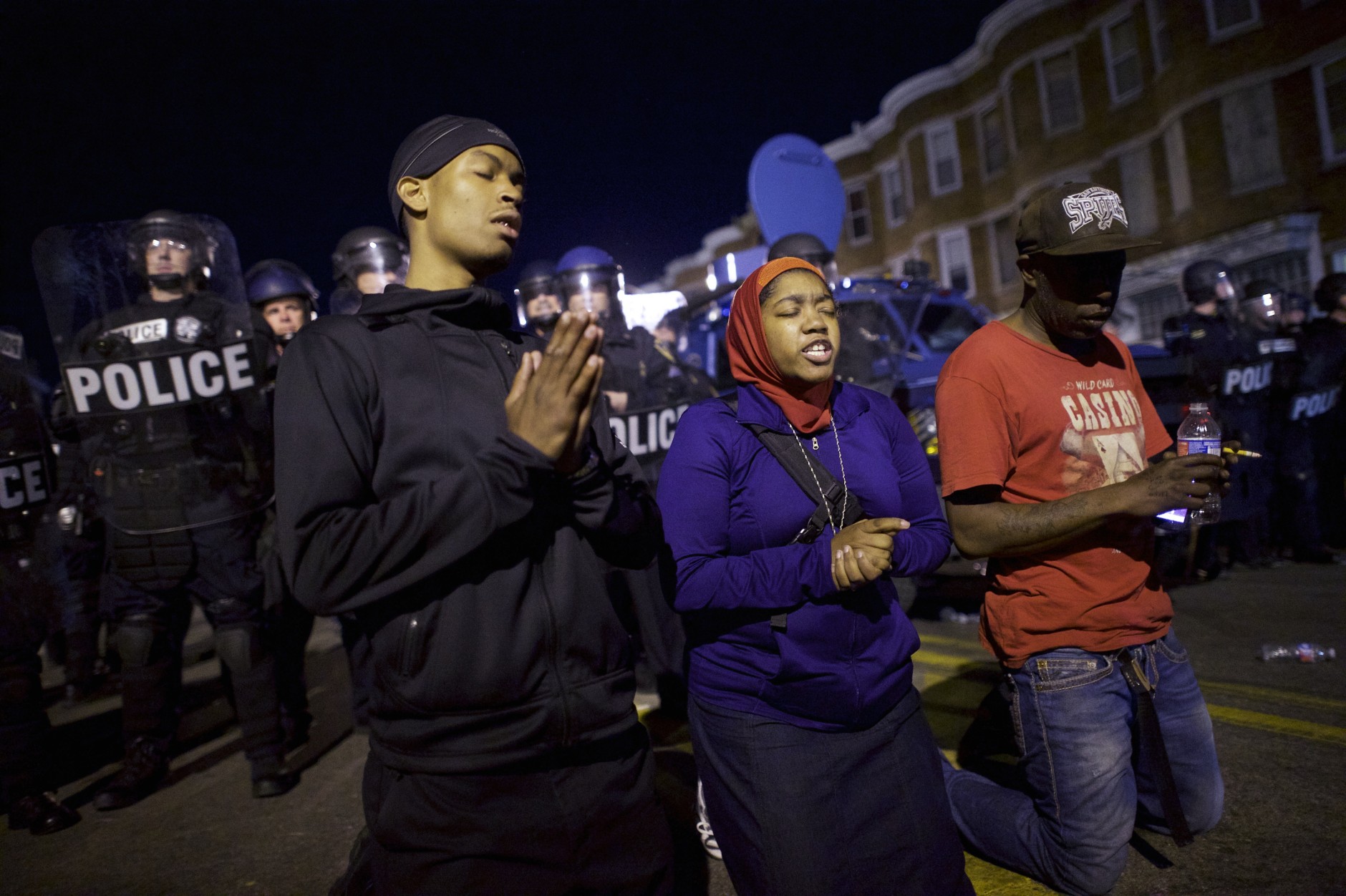 Protestors say the Lord's Prayer beside riot police the night after citywide riots over the death of Freddie Gray on April 28, 2015 in Baltimore, Maryland. Freddie Gray, 25, was arrested for possessing a switch blade knife April 12 outside the Gilmor Houses housing project on Baltimore's west side. According to his attorney, Gray died a week later in the hospital from a severe spinal cord injury he received while in police custody. (Photo by Mark Makela/Getty Images)