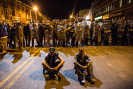 BALTIMORE, MD - APRIL 28:  Two protesters sit on the ground in front of riot police minutes before a mandatory, city-wide curfew of 10 p.m. near the CVS pharmacy that was set on fire yesterday during rioting after the funeral of Freddie Gray, on April 28, 2015 in Baltimore, Maryland. Gray, 25, was arrested for possessing a switch blade knife April 12 outside the Gilmor Houses housing project on Baltimore's west side. According to his attorney, Gray died a week later in the hospital from a severe spinal cord injury he received while in police custody.  (Photo by Andrew Burton/Getty Images)