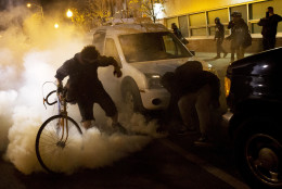 Protesters attempt to throw a tear gas canister back toward riot police after a 10 p.m. curfew went into effect in the wake of Monday's riots following the funeral for Freddie Gray, Tuesday, April 28, 2015, in Baltimore. (AP Photo/David Goldman)