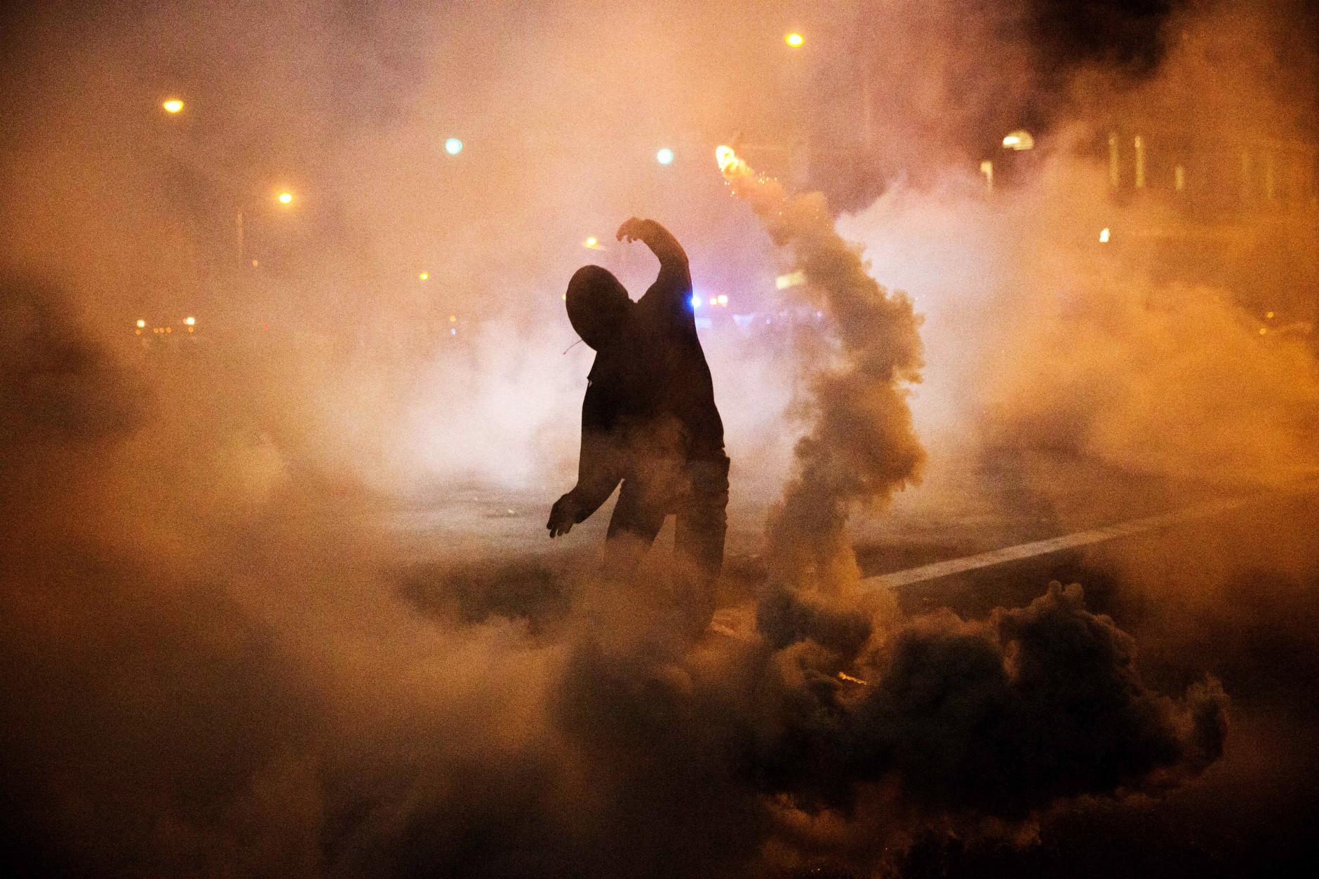 A protester throws a tear gas canister back toward riot police after a 10 p.m. curfew went into effect in the wake of Monday's riots following the funeral for Freddie Gray, Tuesday, April 28, 2015, in Baltimore. (AP Photo/David Goldman)